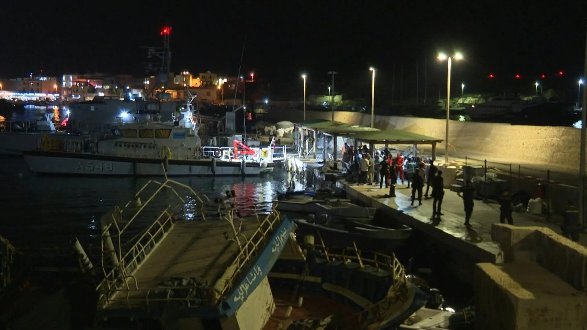 Migrants disembark and receive aid off Lampedusa coast